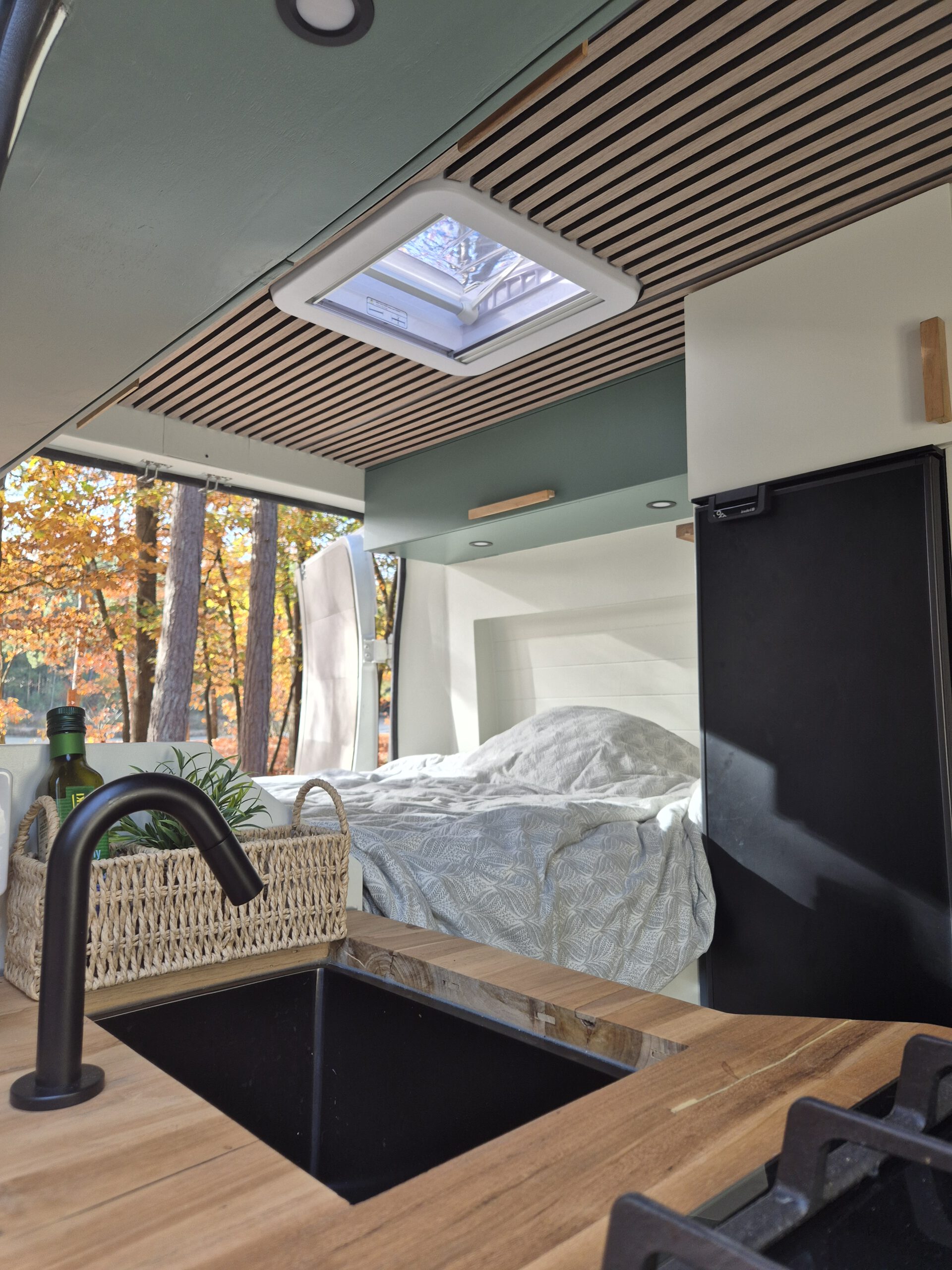 Vanaf het keukentje kijk je naar het bed in camper Jade
